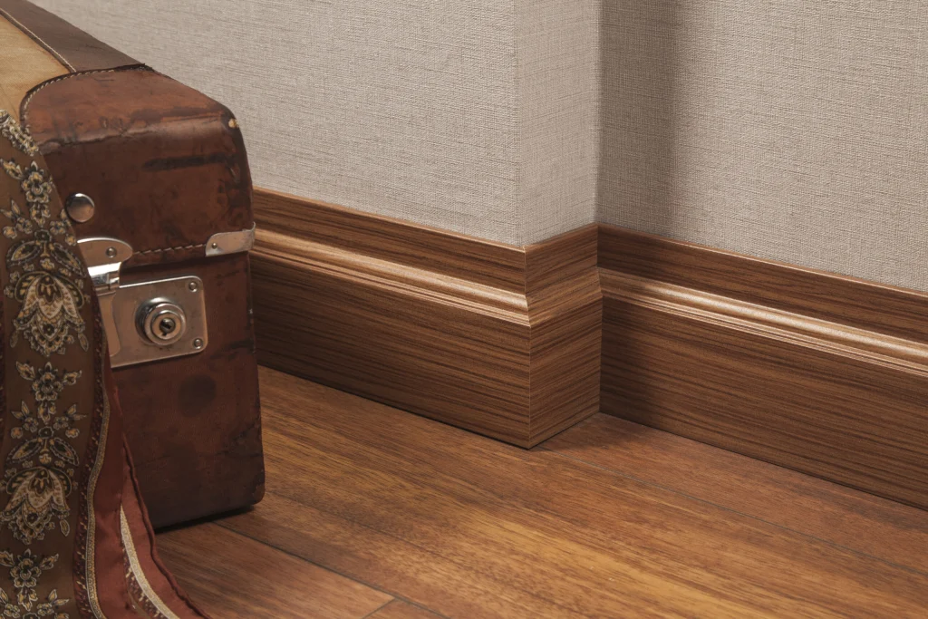 Foil-wrapped MDF skirting fitted along a wall above a laminate floor